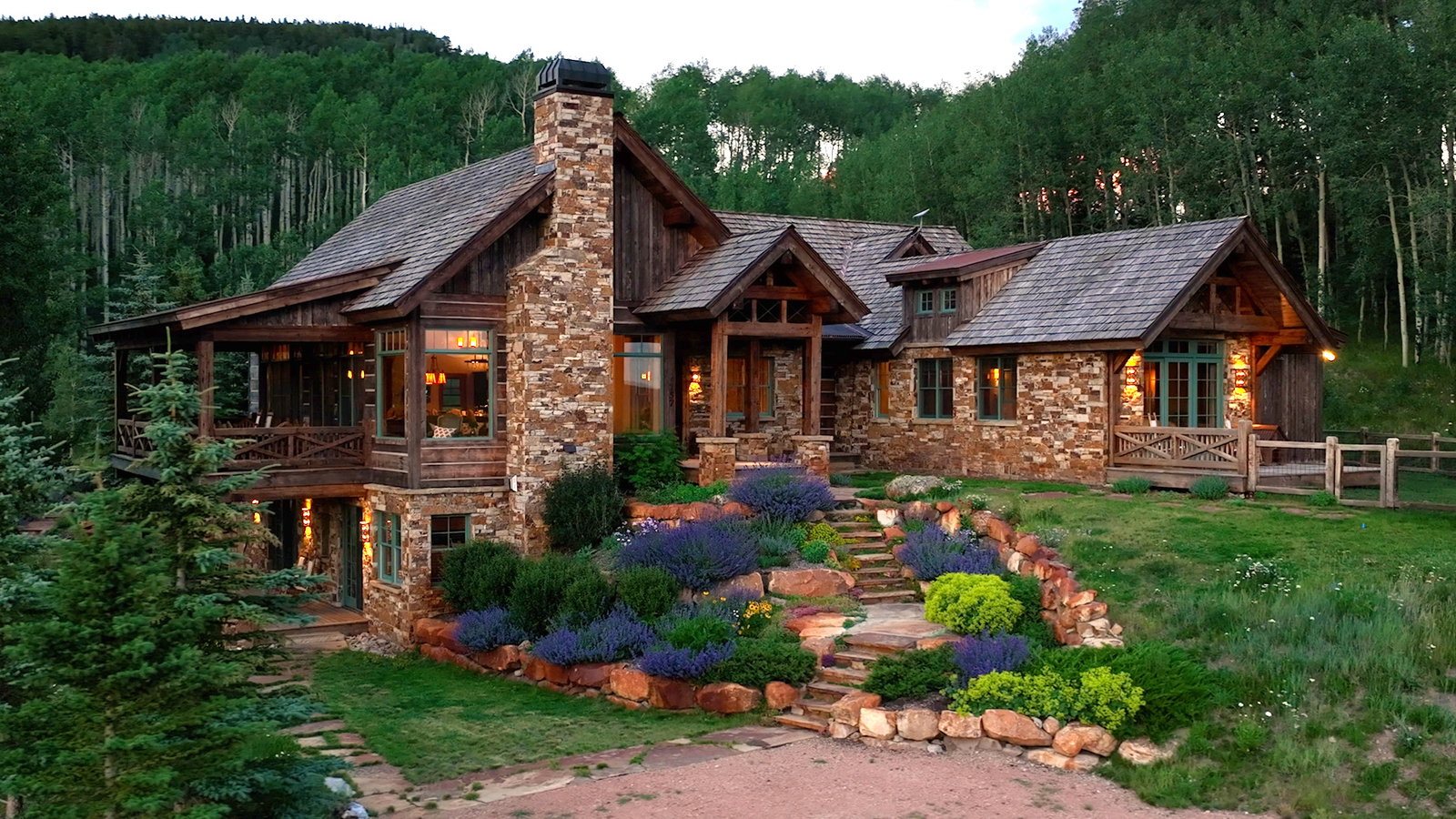 Twilight exterior of a stone and timber mountain home near Crested Butte, Colorado, represented by Jana Barrett